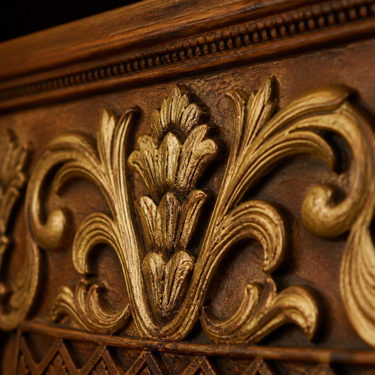 Macro detail of hand-carved solid teak panel with antique gold leaf floral carving